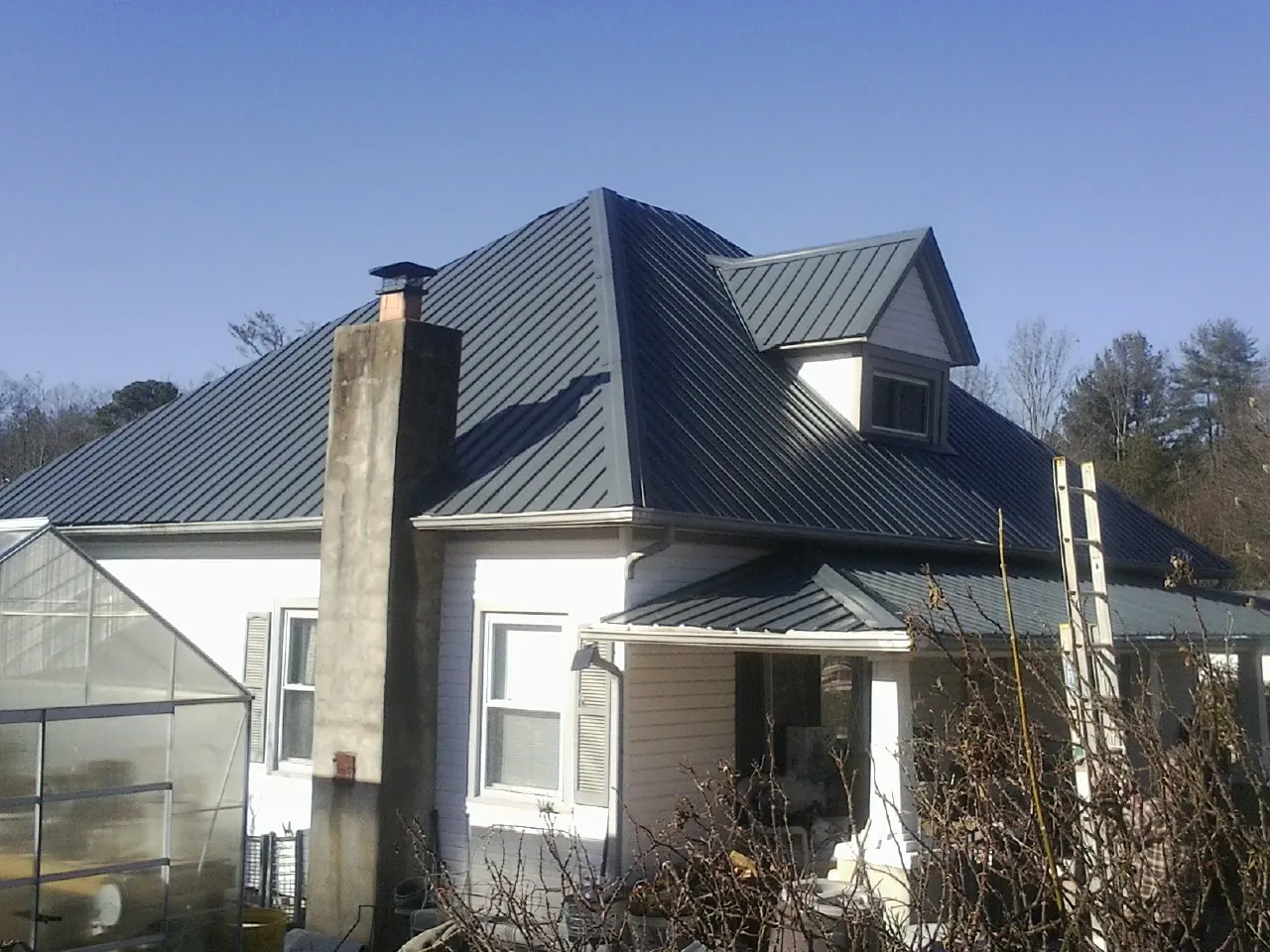 Dark blue standing seam metal roof on a white farmhouse with dormer — Slate & Tile Roof Repair by Roofing Brothers in Montreat