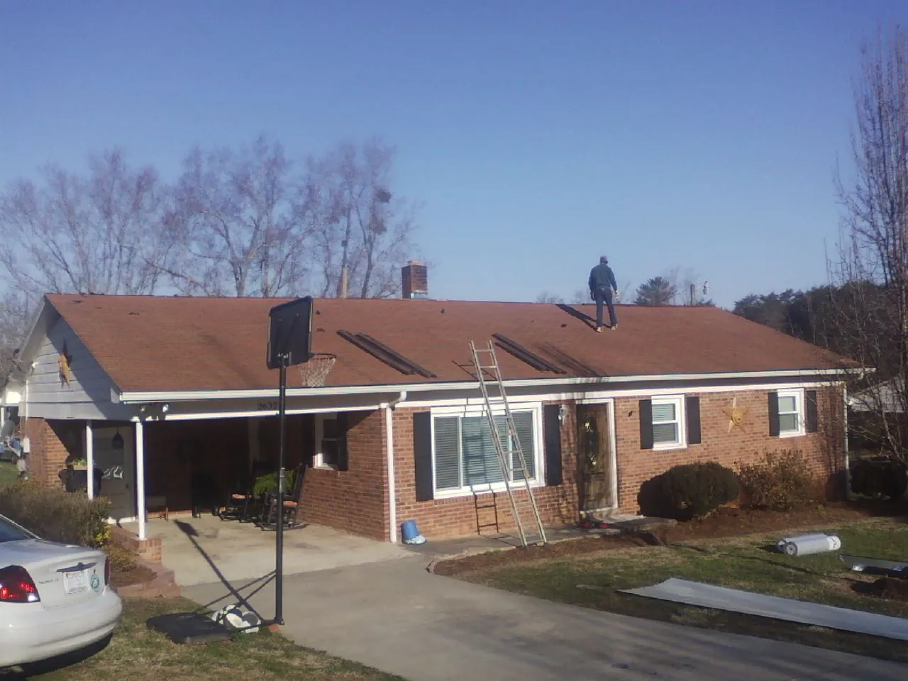 Roofer stripping a shingle roof on a brick ranch before metal panels in Montreat