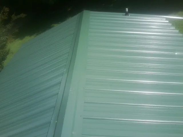 New green metal panels meeting at the ridge of a roof — Flat Roof Repair work by our crew in Montreat