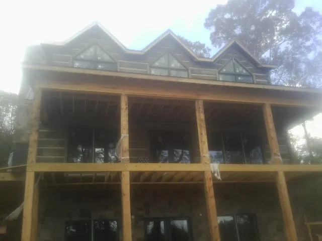 Dormers and porch framing on a large log home under construction — Roof Coating work by our crew in Montreat