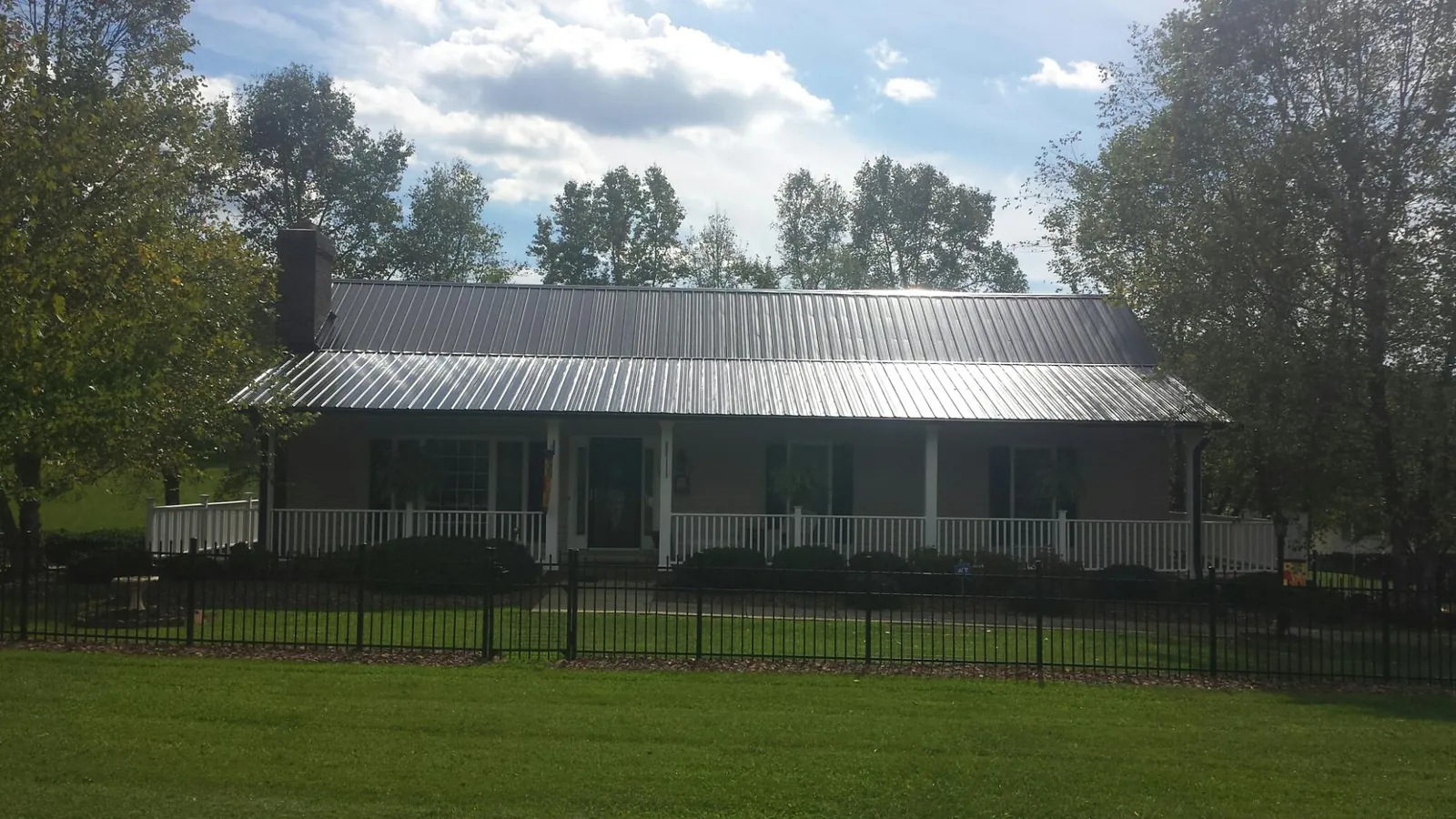 Gray metal roof on a brick ranch with a full width front porch — Gutter Guard Installation work by our crew in Montreat
