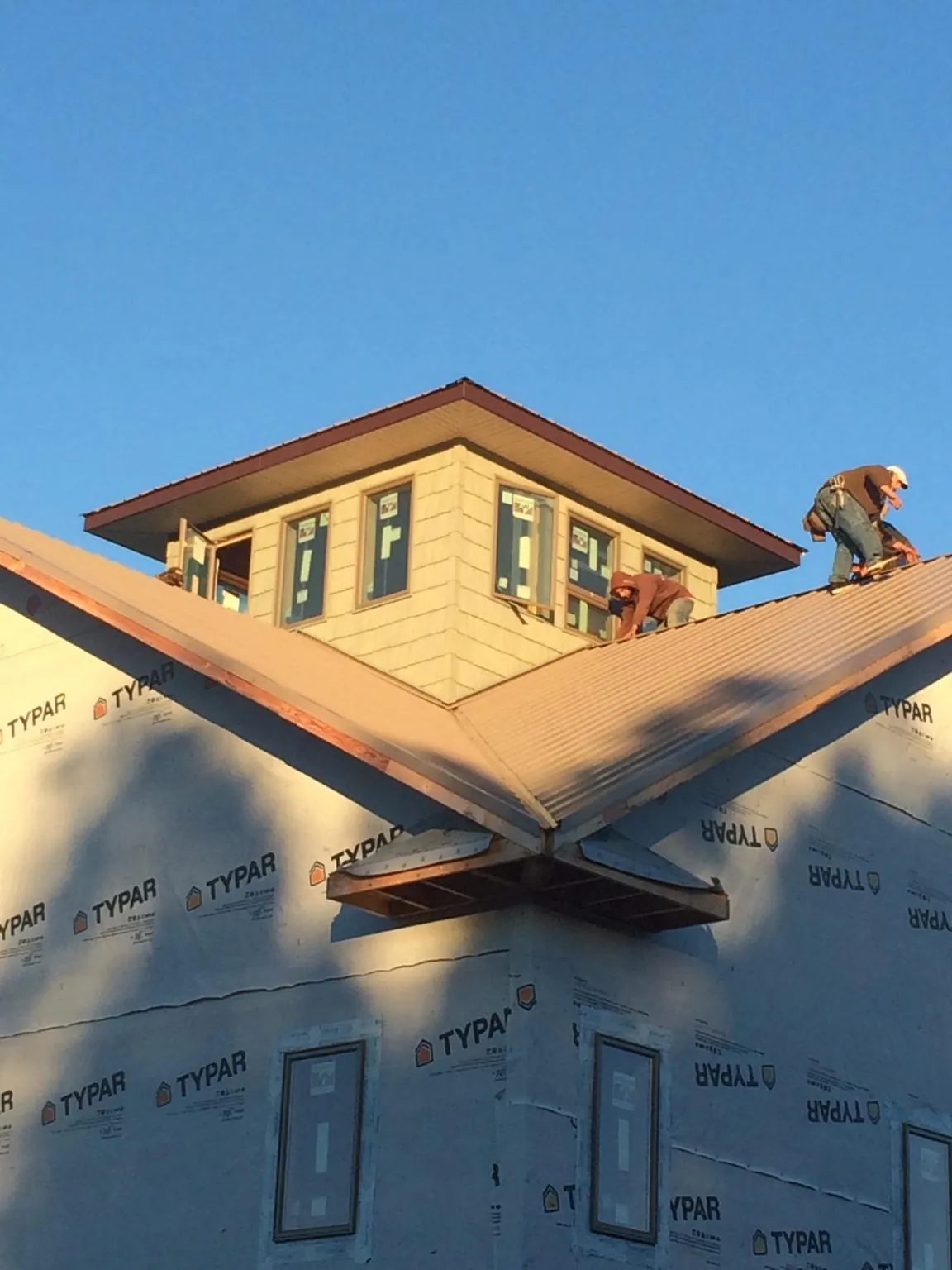 Roofers working around a rooftop cupola on a new metal roof at sunset — Roof Waterproofing in Montreat by Roofing Brothers